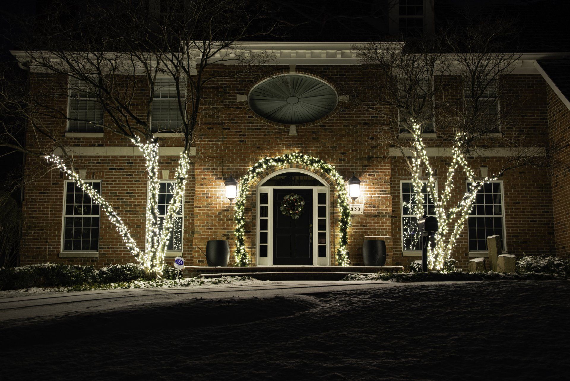 A large brick house decorated with christmas lights at night
