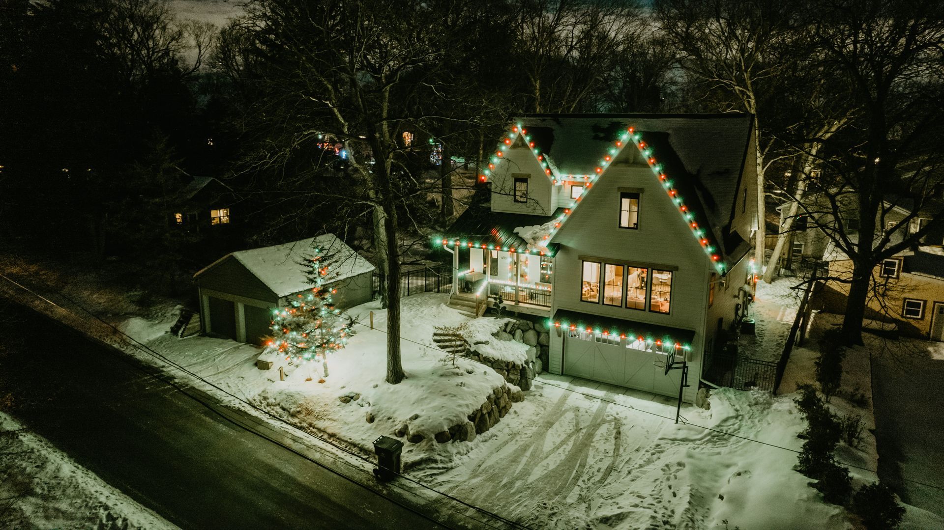 An aerial view of a house decorated with christmas lights at night.