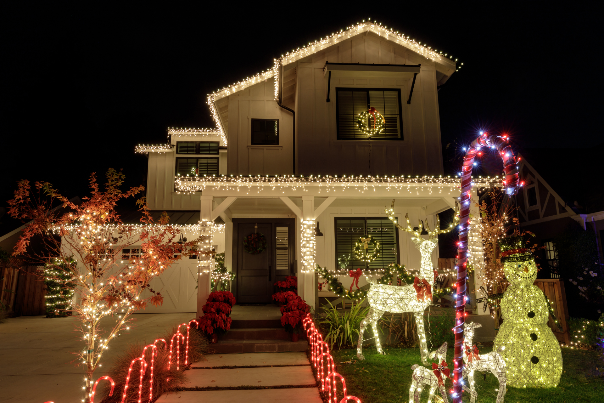 A house is decorated with christmas lights and decorations at night.