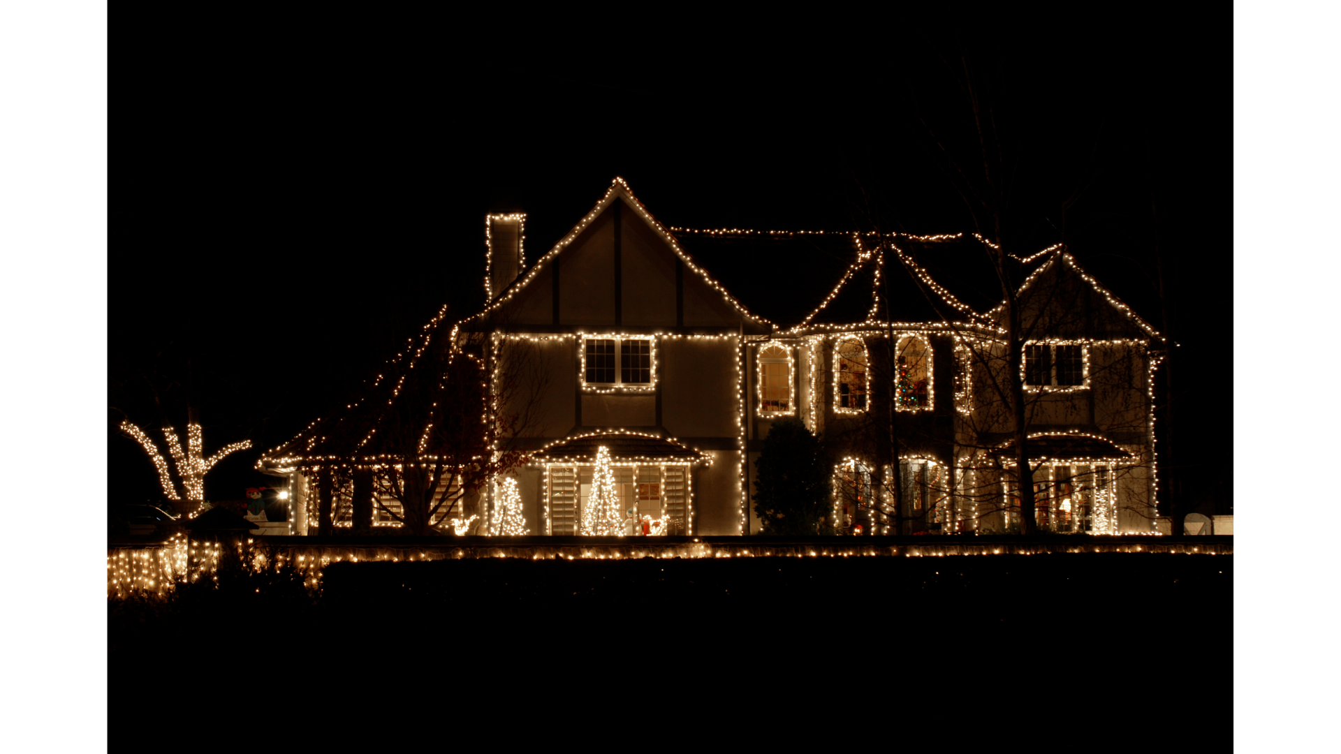 Holiday lights outlining the roof and landscaping of a home in Edina, MN