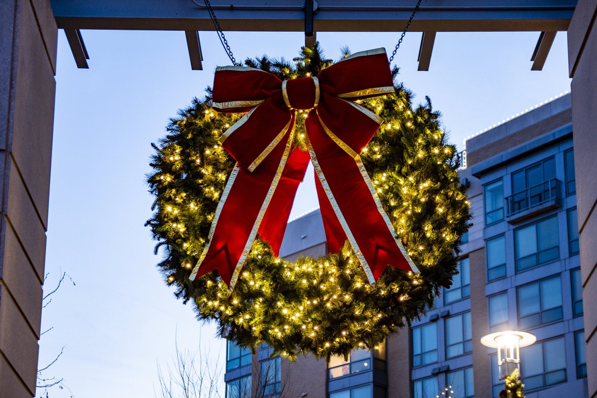 A christmas wreath with a red bow is hanging from a building.