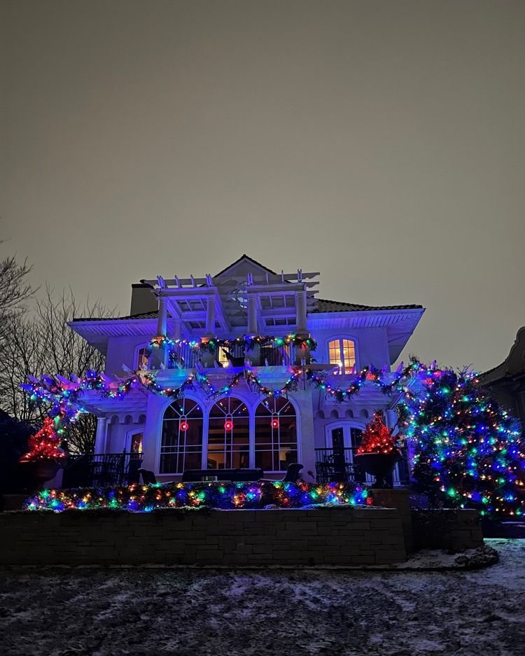 Holiday lights reflecting off snow-covered trees and rooftops in Woodland, MN’s Shadywood area