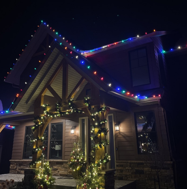 Twinkling holiday lights on a snow-covered Eden Prairie, MN house surrounded by trees