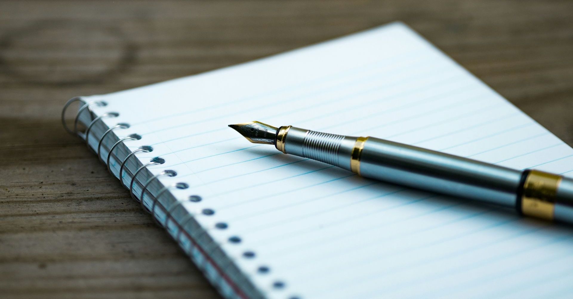 a pen is sitting on top of a notebook on a wooden table 