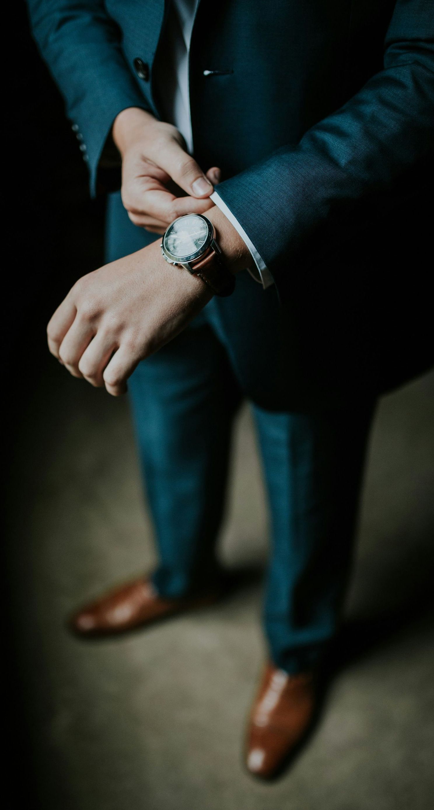 a man in a suit is adjusting his watch on his wrist 