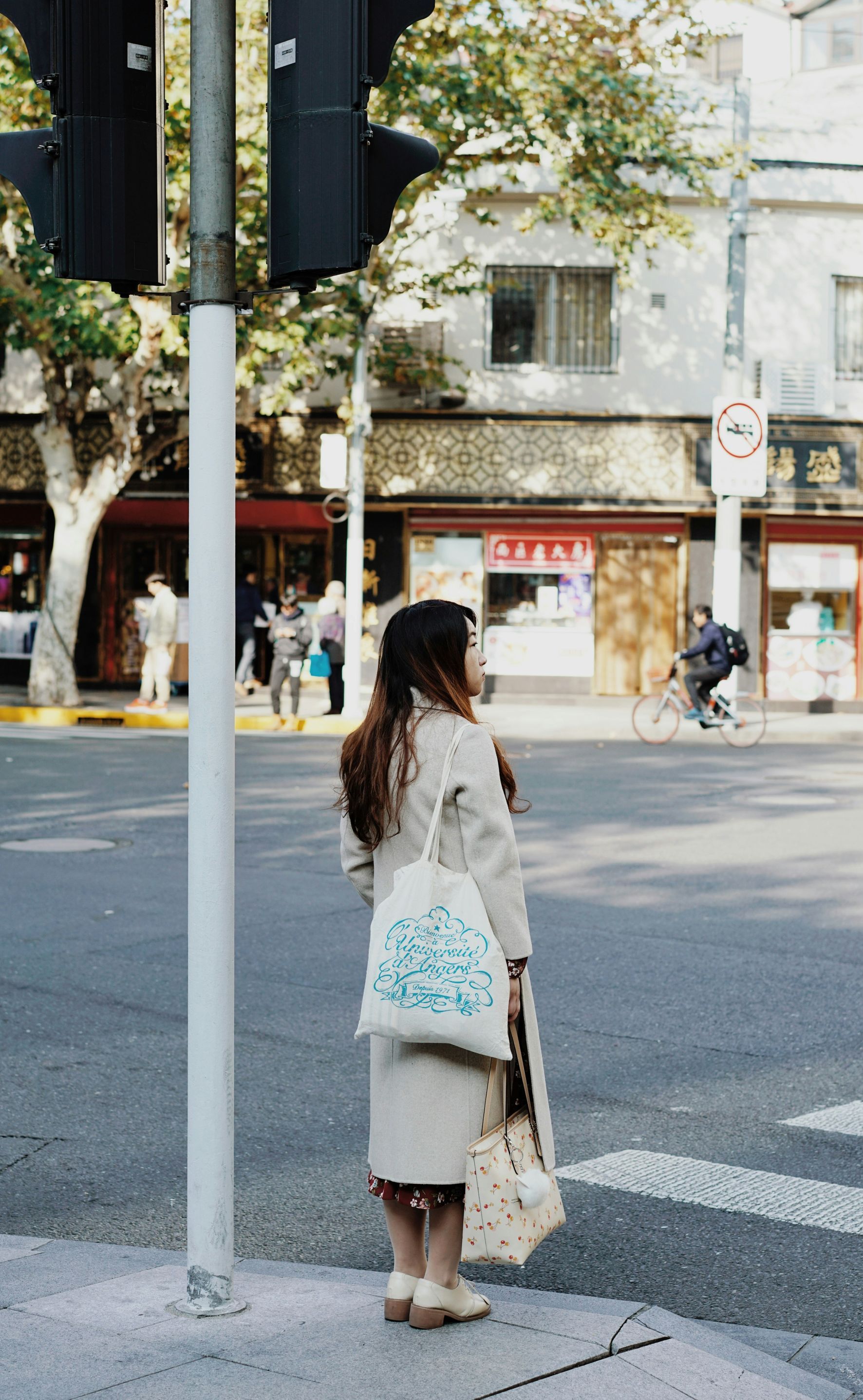 A woman is waiting at a traffic light to cross the street.