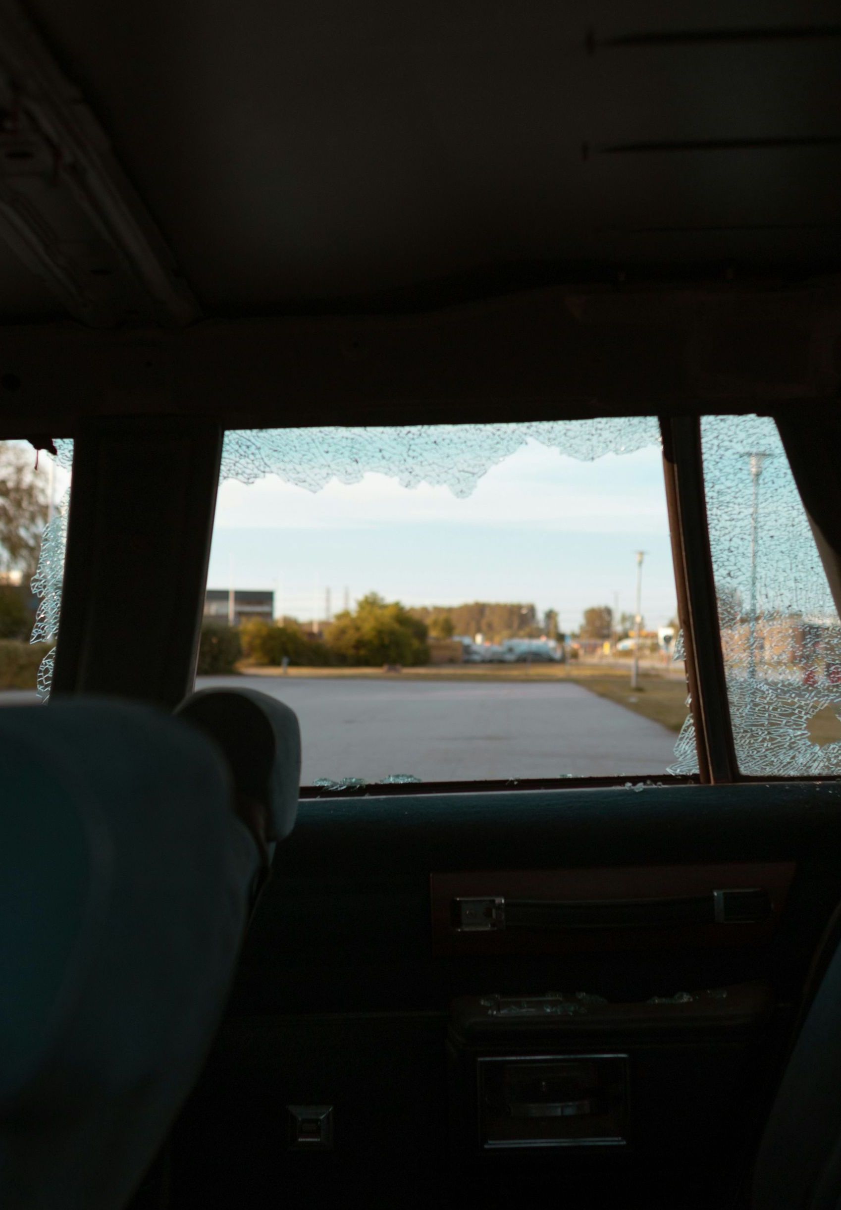 A car with a broken windshield is driving down a road.