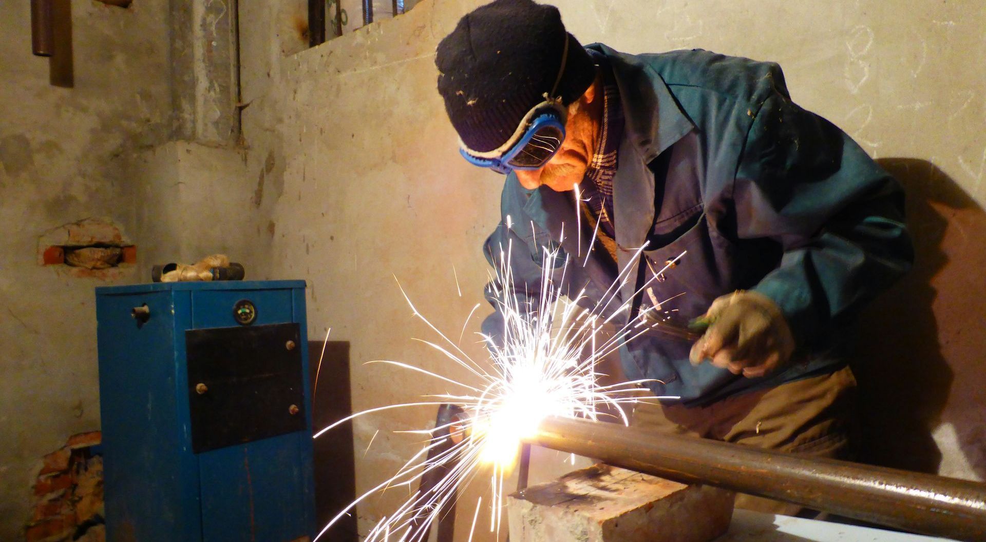 A man is welding a pipe with sparks coming out of it.