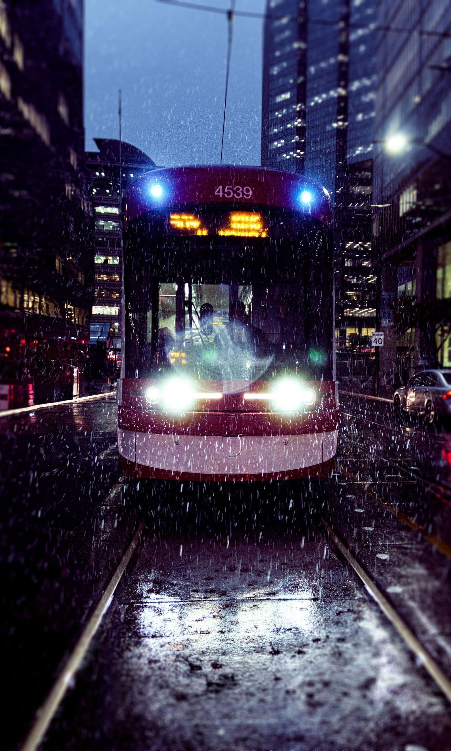 A trolley is driving down a city street at night