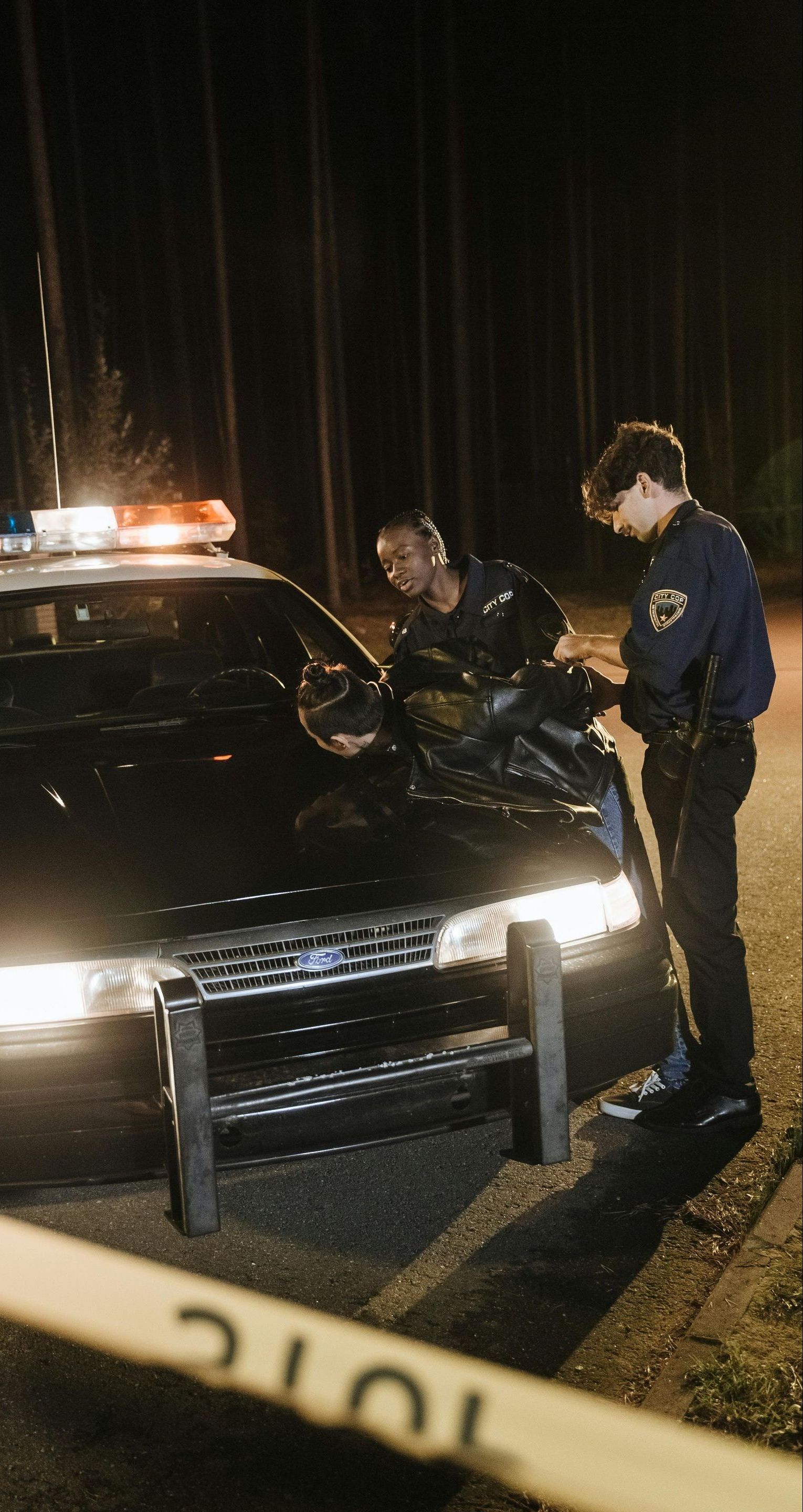 Two police officers are standing next to a police car.