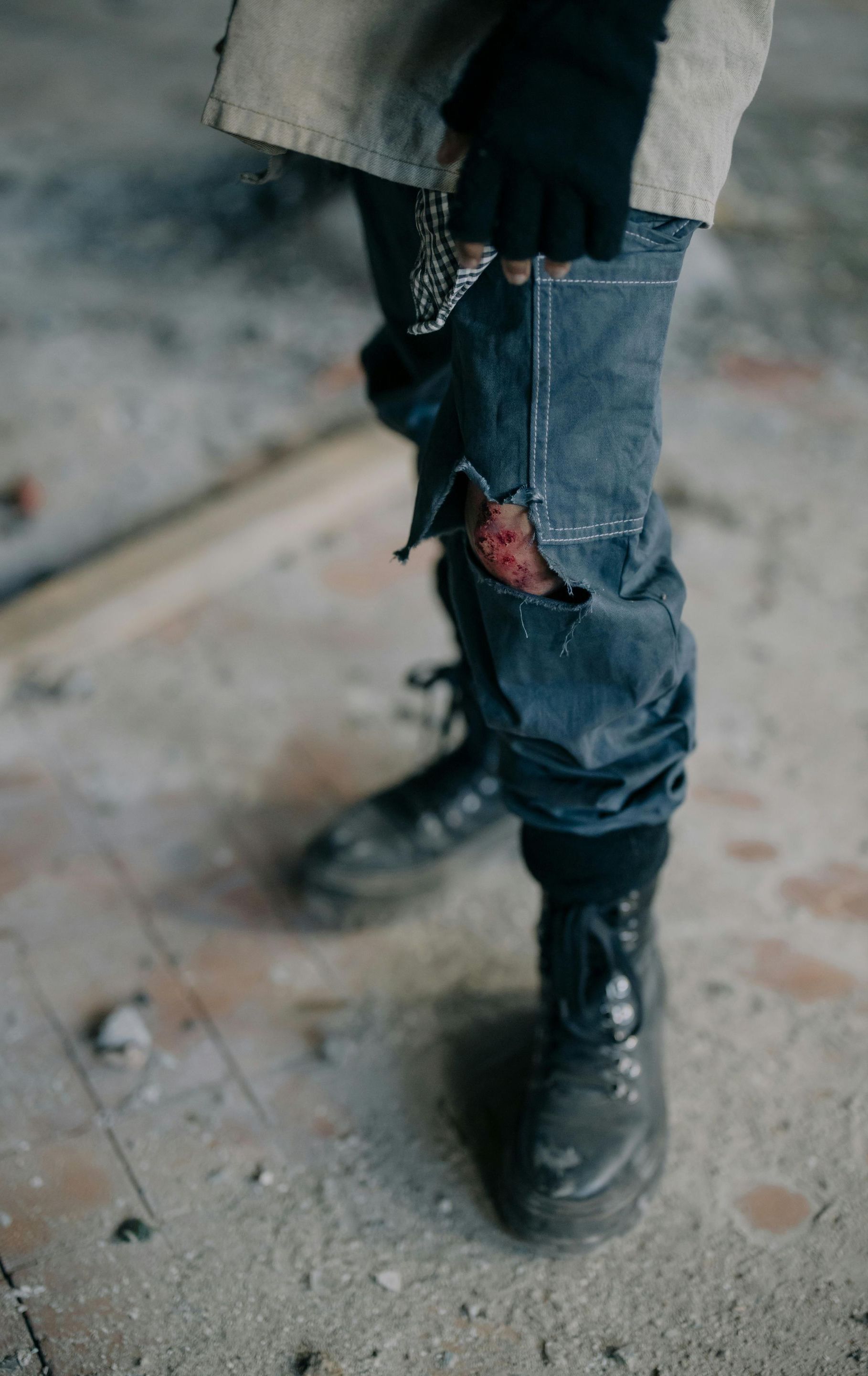 A person wearing a pair of black boots and jeans is standing on a concrete floor.