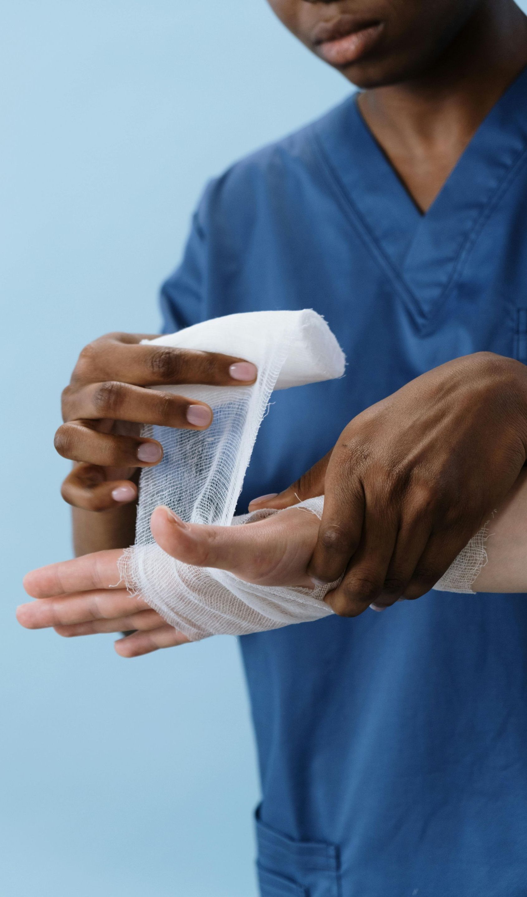 A nurse is wrapping a patient 's wrist with a bandage.