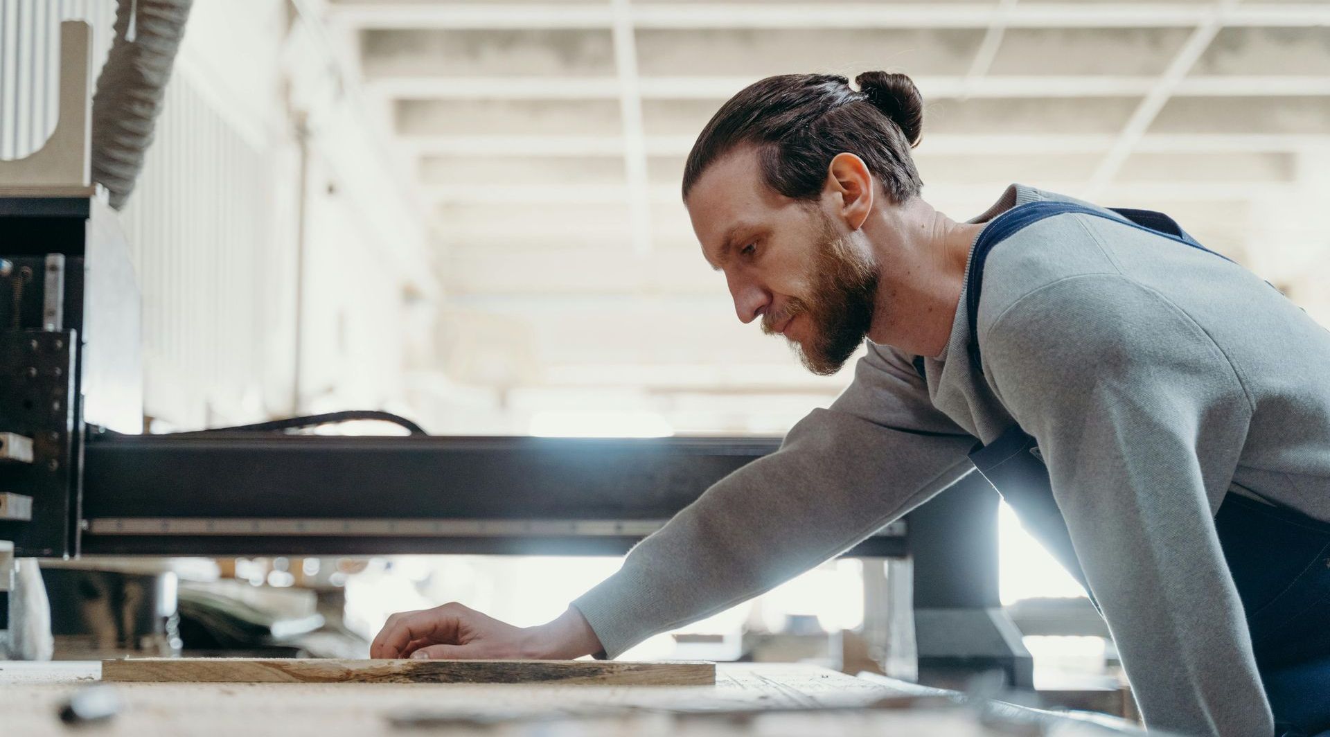 A man is working on a piece of wood in a workshop.