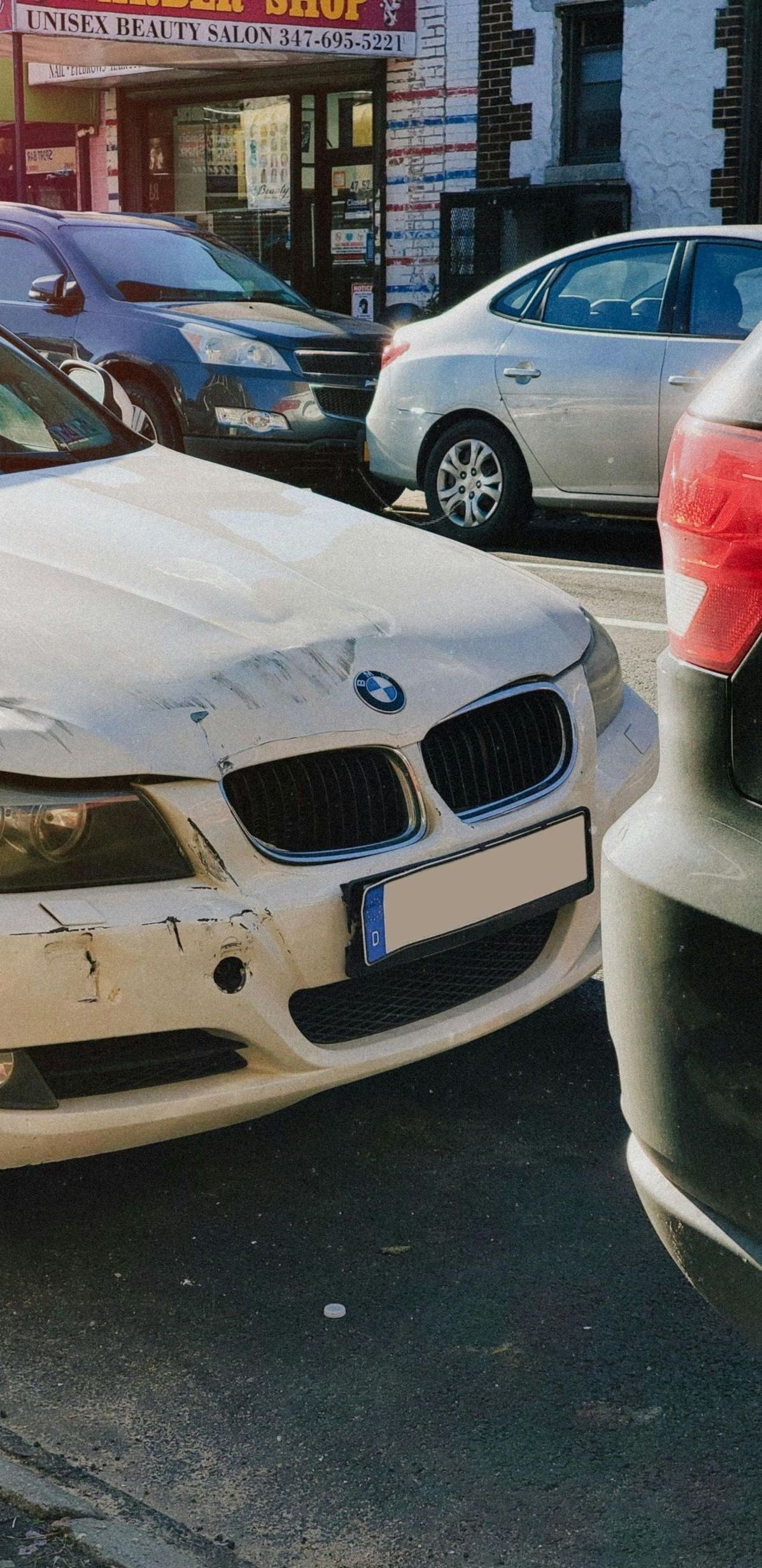 A bmw is parked on the side of the road next to another car.