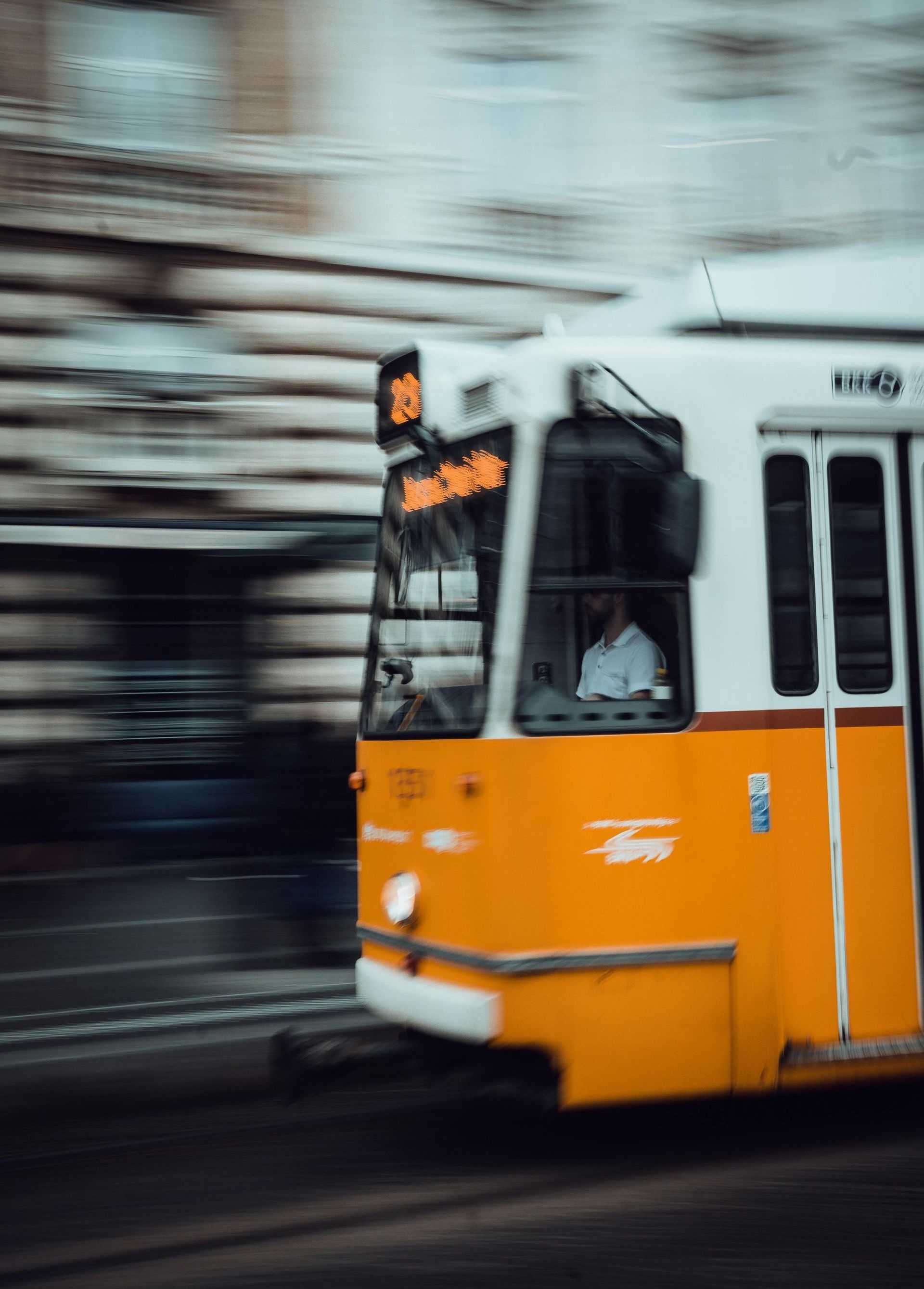 A yellow and white bus is driving down a street.