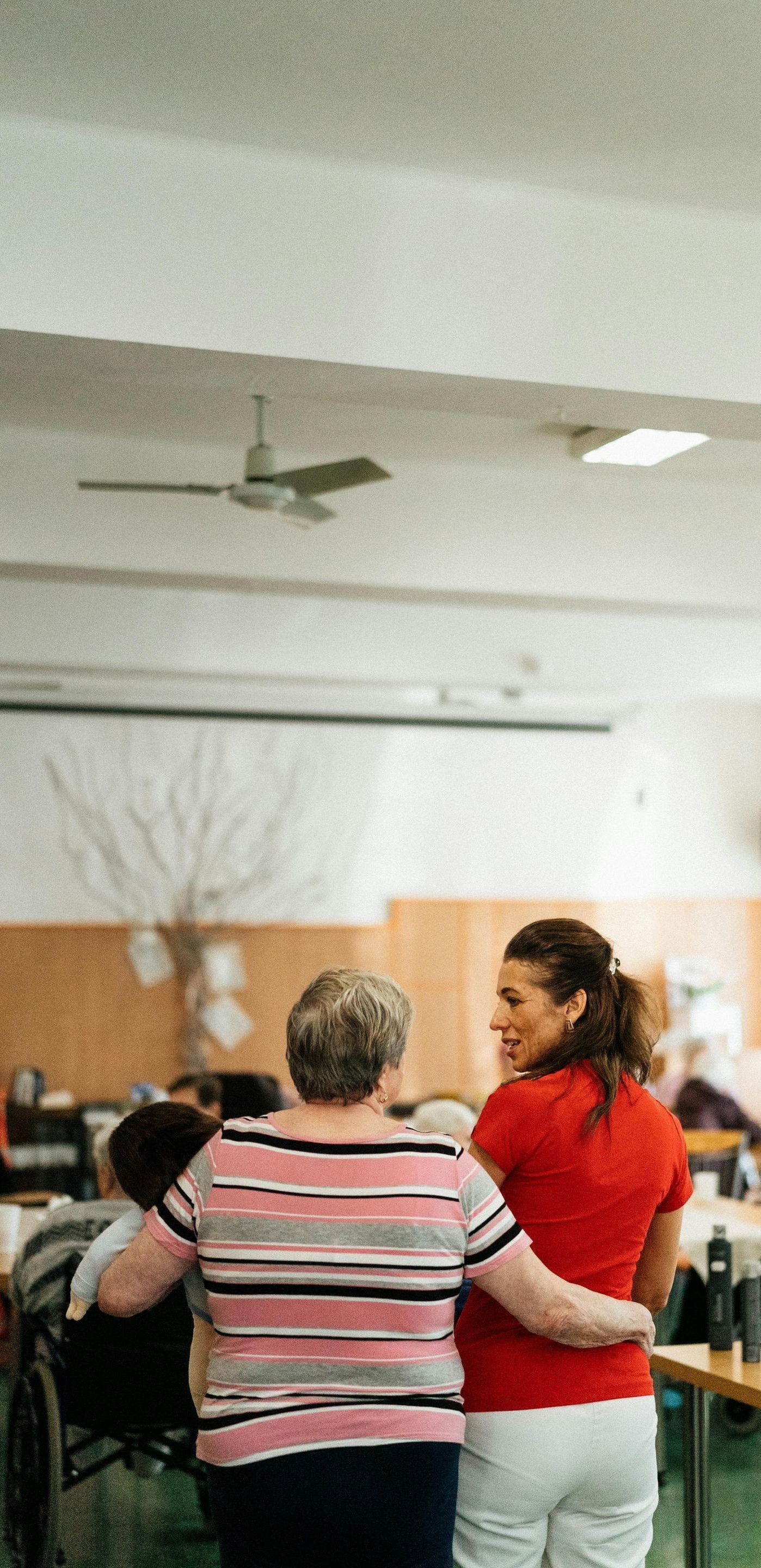 A woman is walking with an elderly woman in a wheelchair.