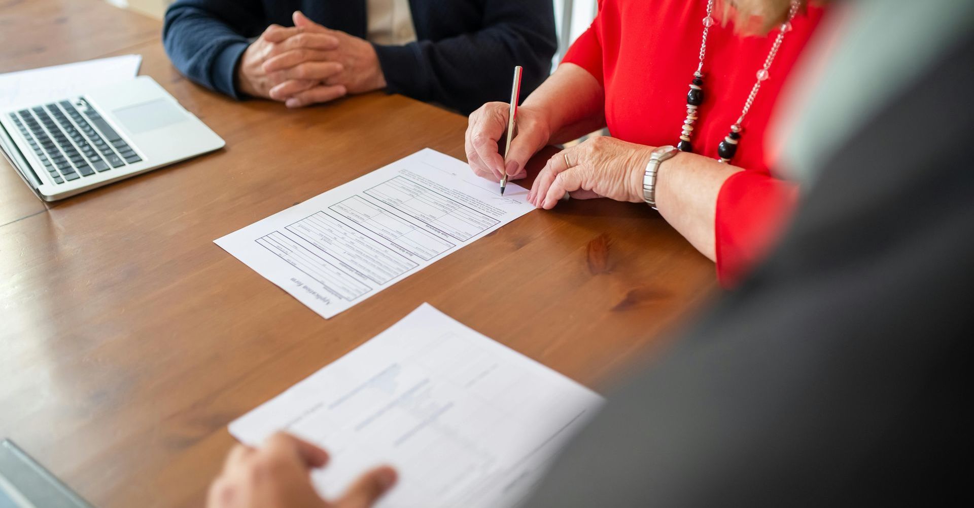 A group of people are sitting at a table signing a document.