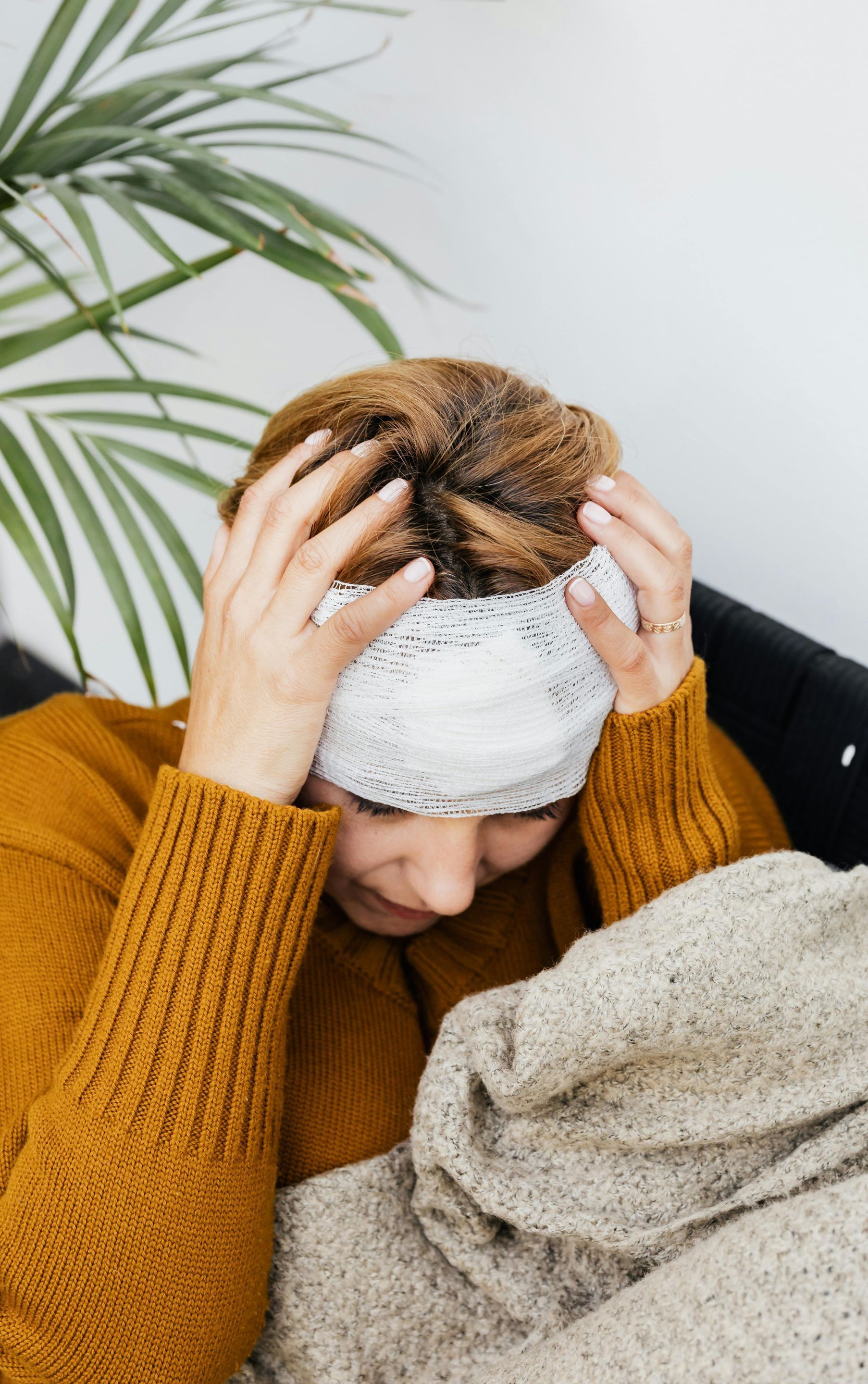 a woman is laying on a couch with a bandage on her head