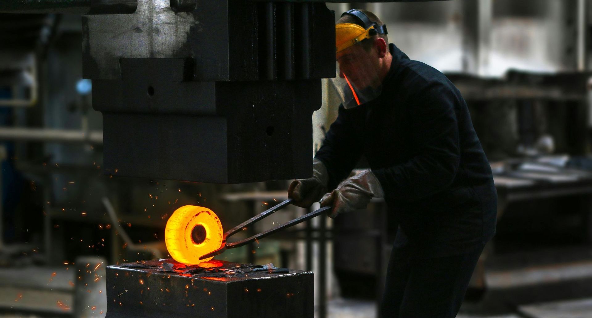 A man is working on a piece of metal in a factory.