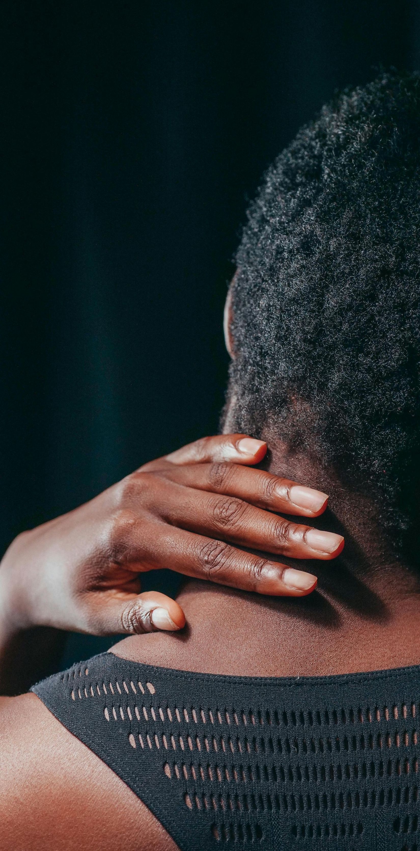 A person is touching their neck with their hand.