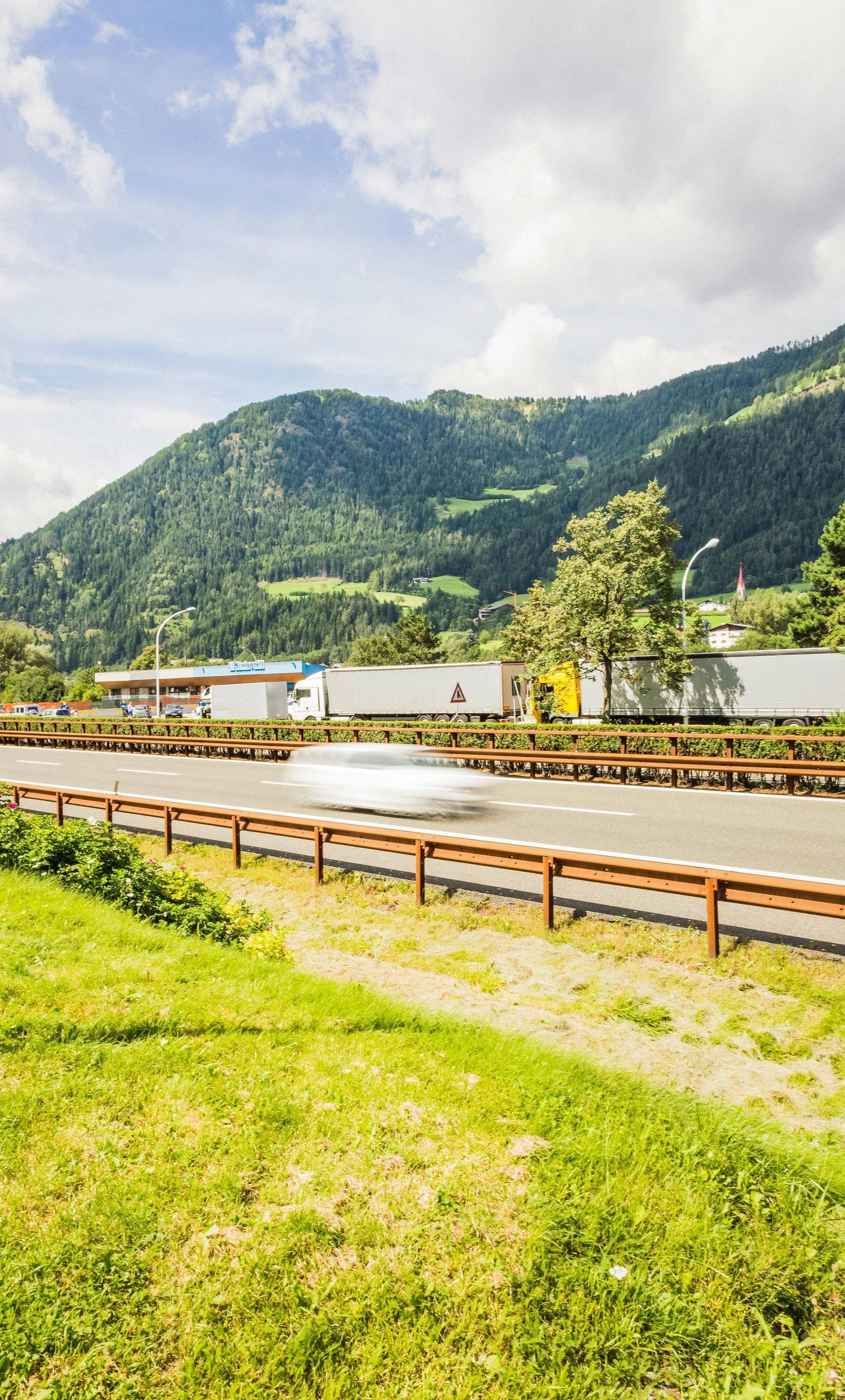 A car is driving down a highway with mountains in the background.