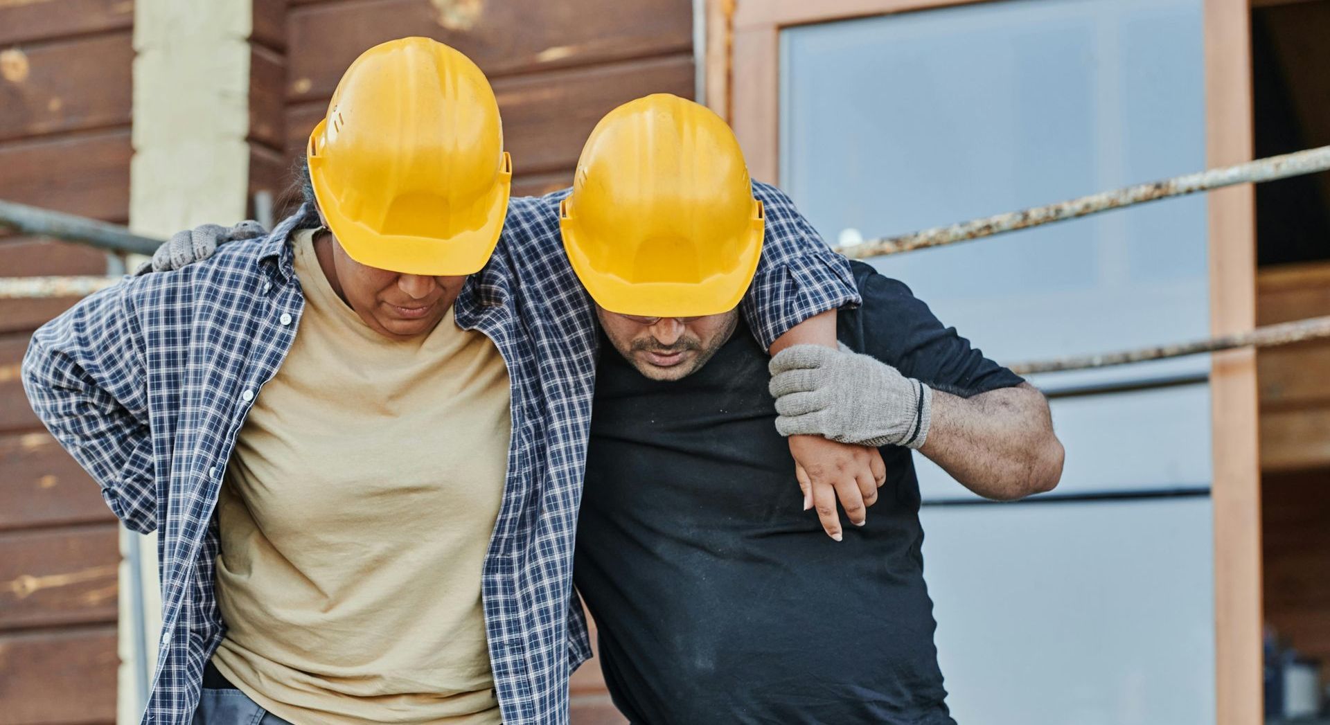 2 men wearing hard hats are helping each other