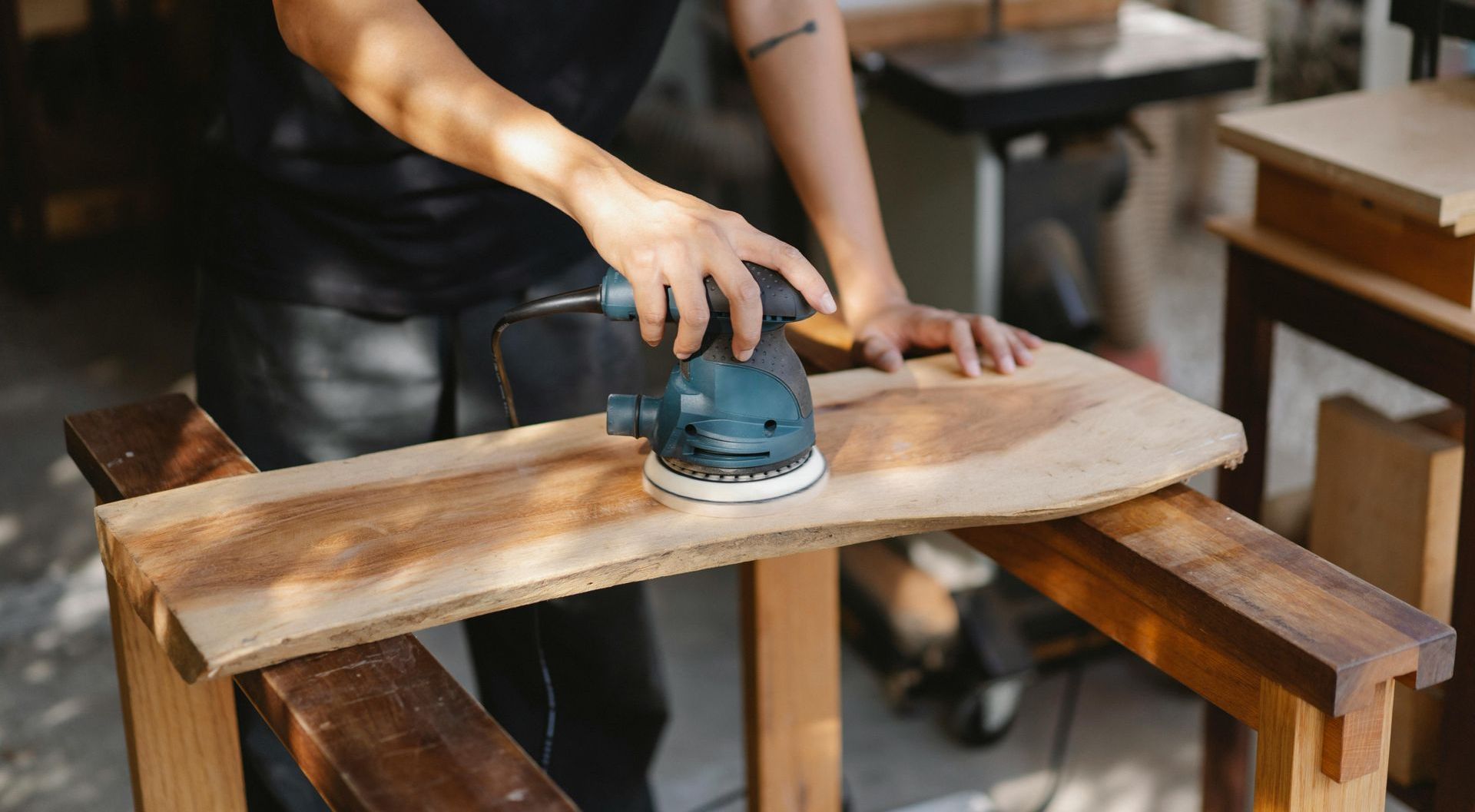 A person is sanding a piece of wood with a sander.