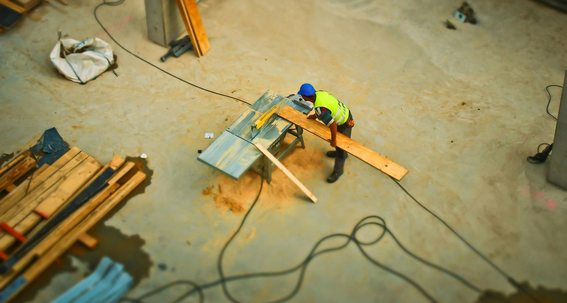 A man is cutting a piece of wood on a table saw.