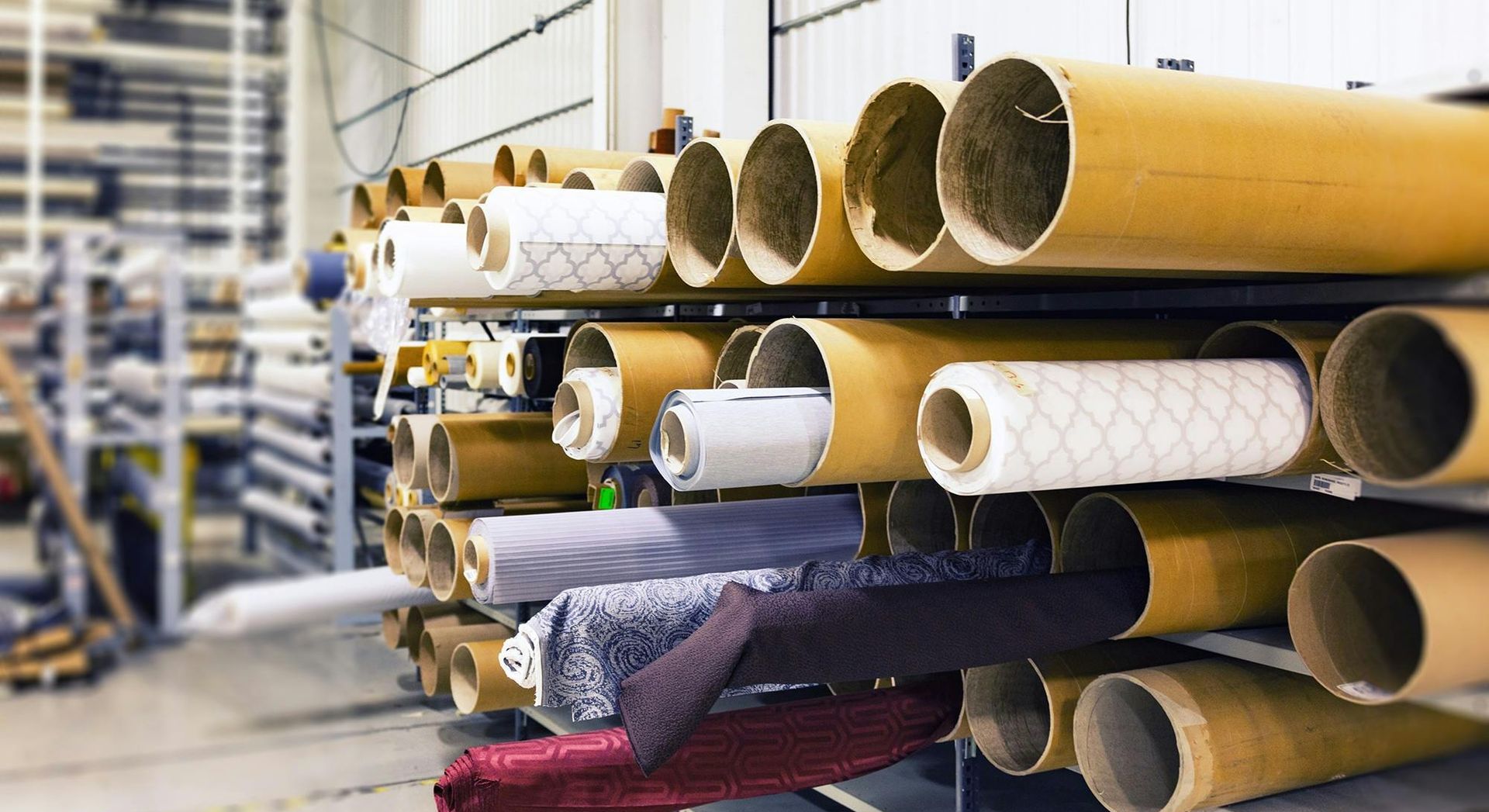 Rolls of fabric are stacked on top of each other in a warehouse.