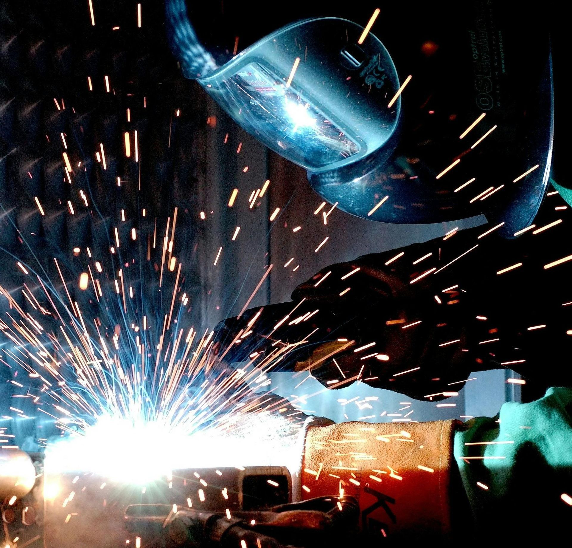 A man is welding a piece of metal with sparks coming out of it