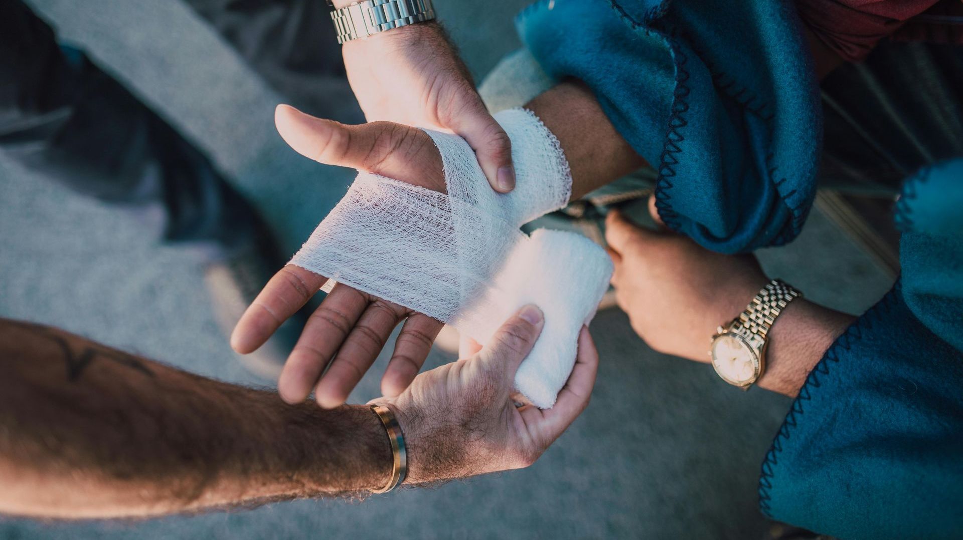 A person is wrapping another person 's hand with a bandage.