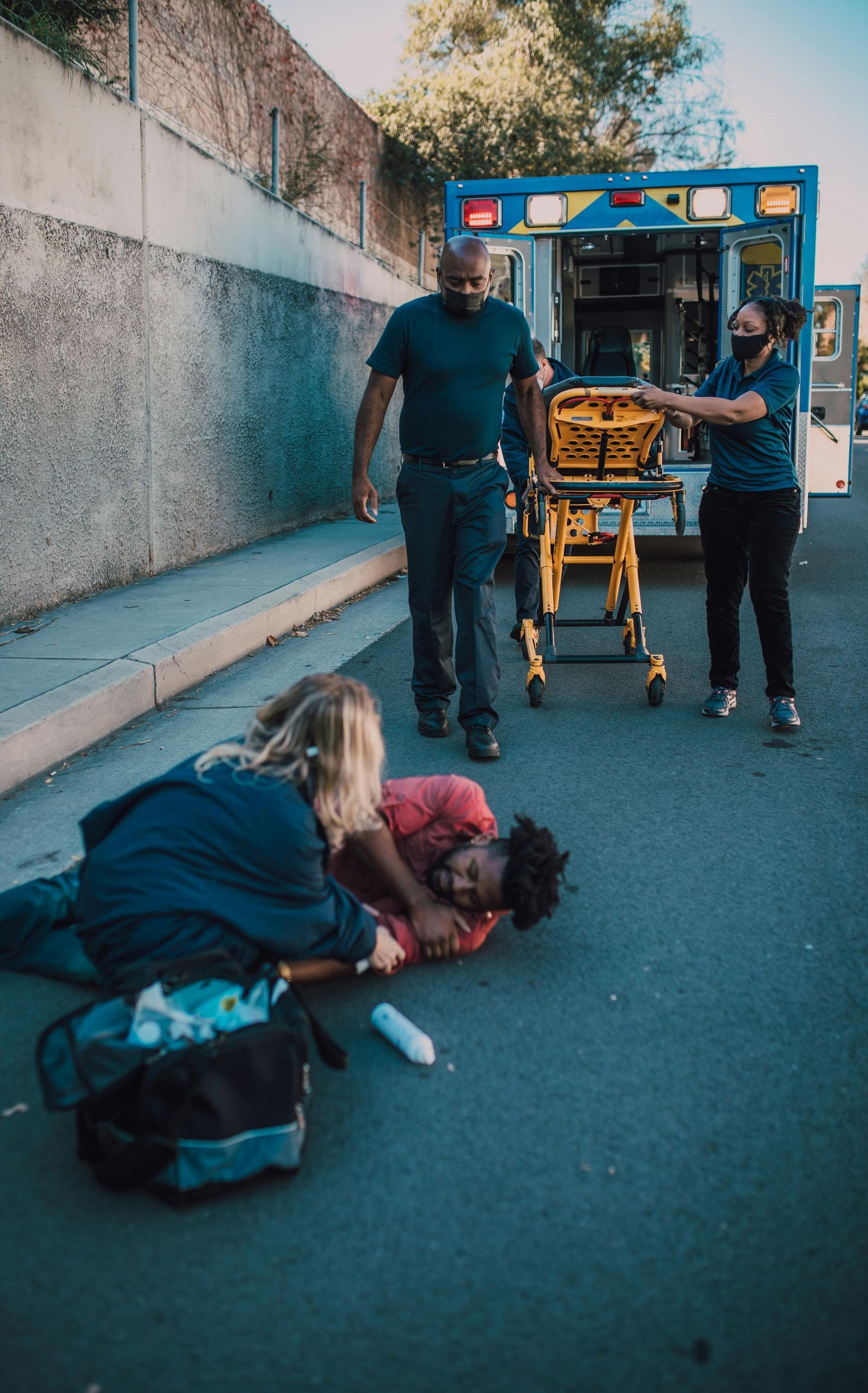 A man is laying on the ground with an ambulance in the background.