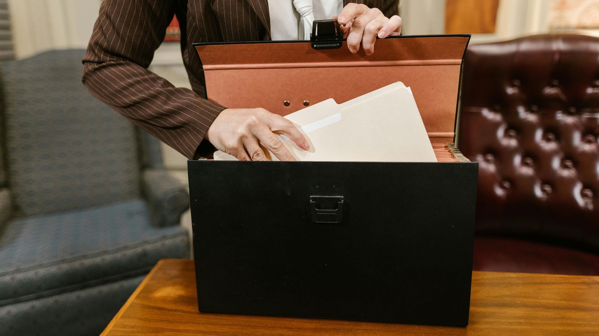 A woman is opening a briefcase filled with papers.