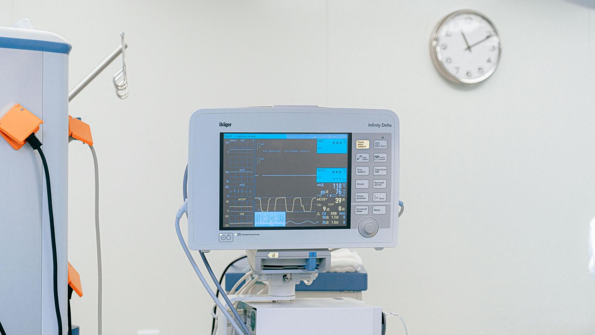 A hospital room with a monitor and a clock on the wall.