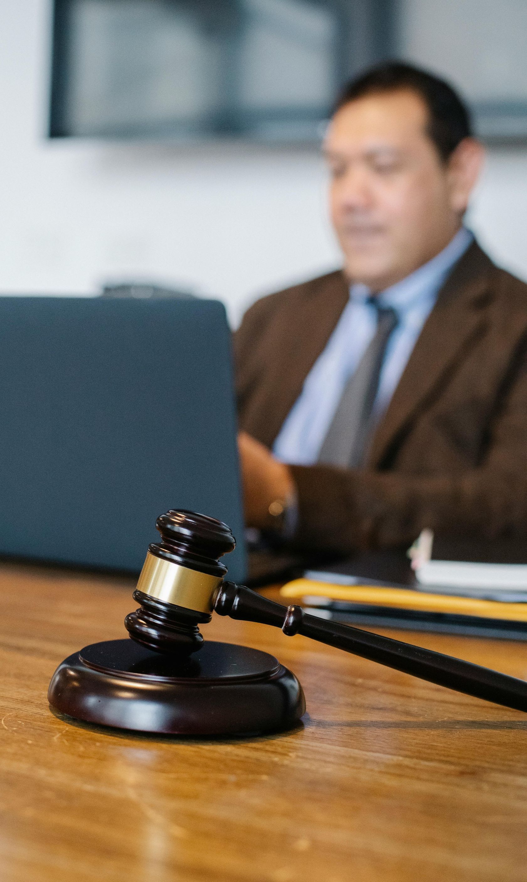A judge 's gavel is sitting on a wooden table in front of a laptop computer.