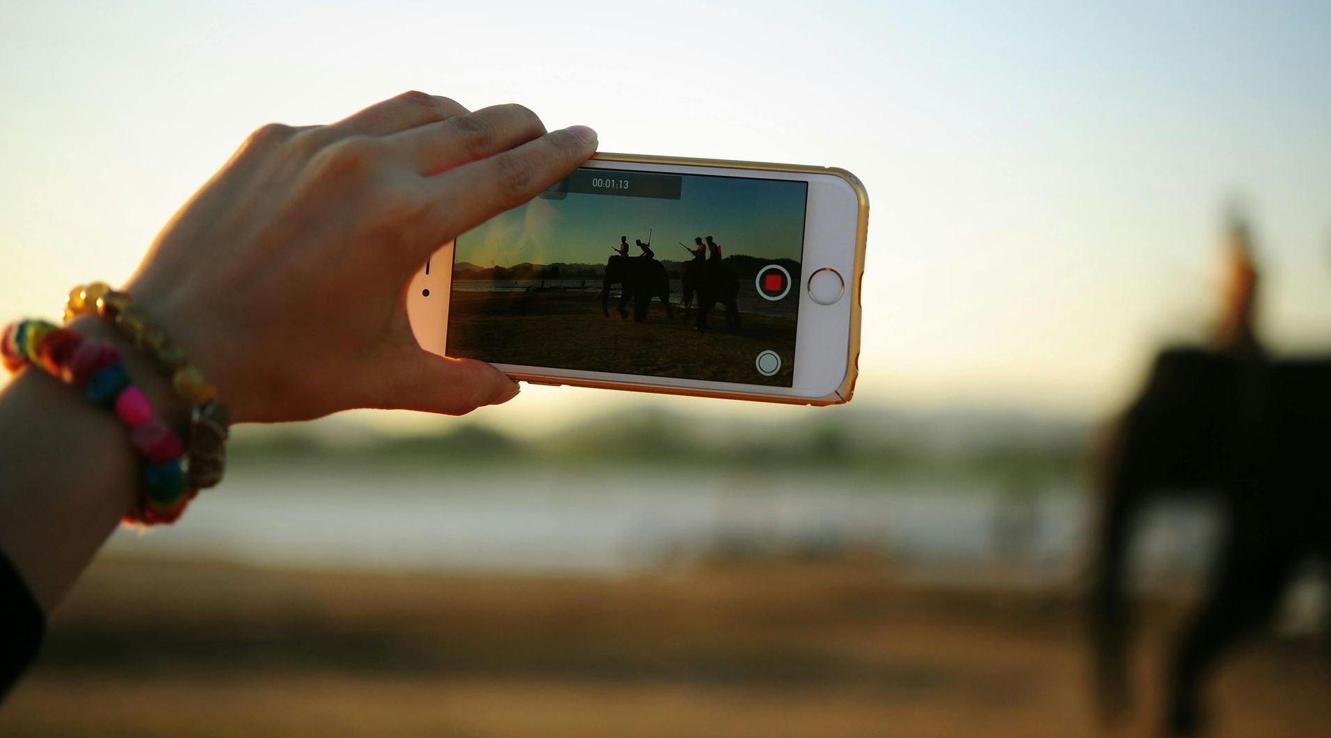 A person is taking a picture of an elephant with a cell phone.