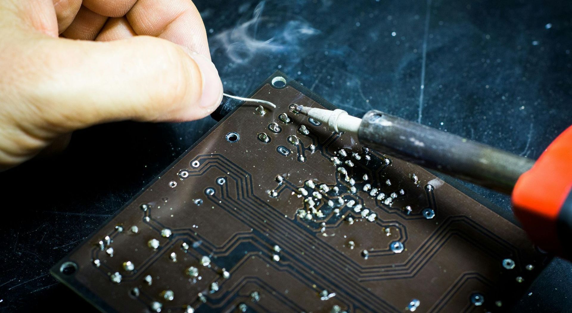 A person is soldering a circuit board with a soldering iron.