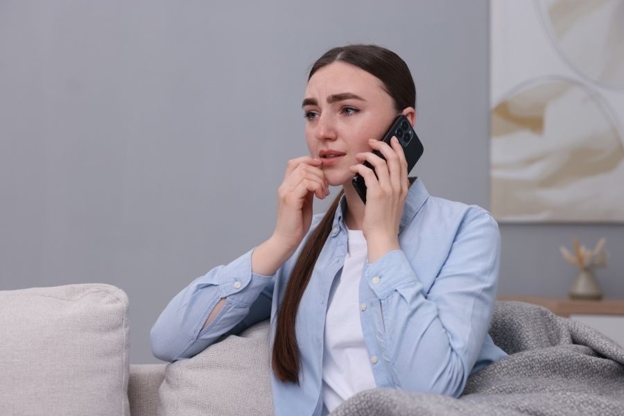 Worried homeowner calling for emergency water damage help from her living room