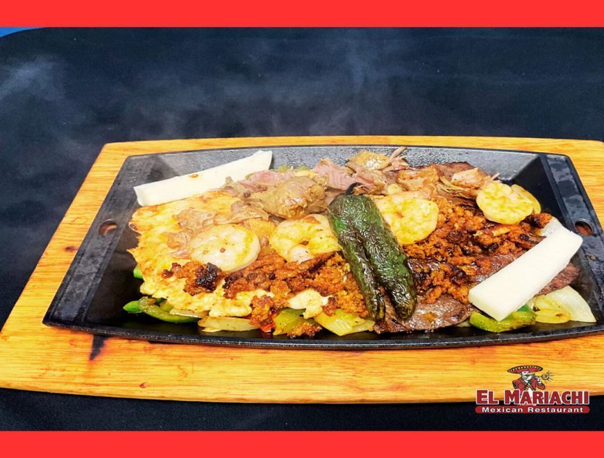 Sizzling fajitas on a hot metal platter with steak, shrimp, peppers, and cheese, on a wooden board.