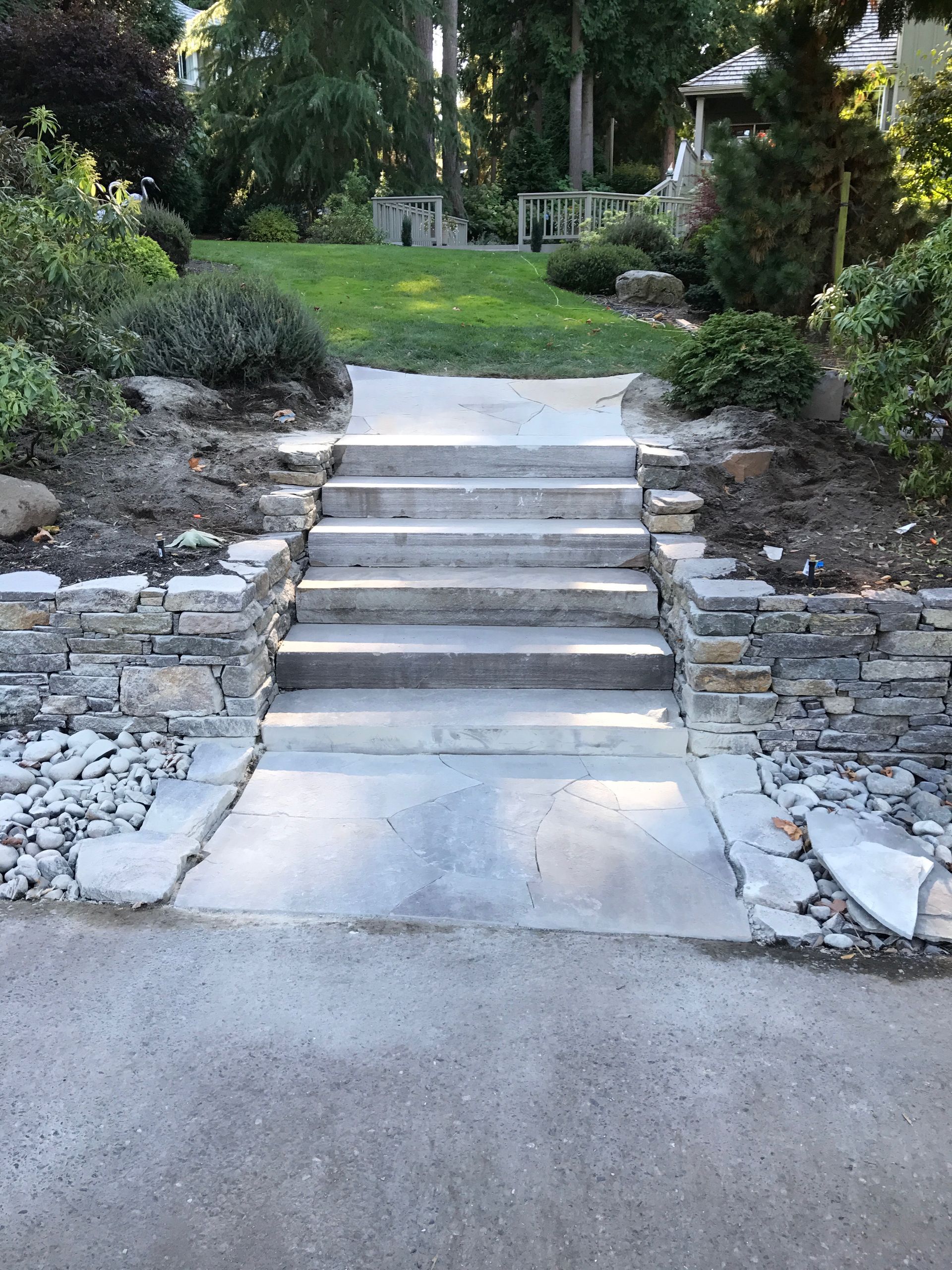 Stone steps leading up to a landscaped garden path with greenery on both sides.