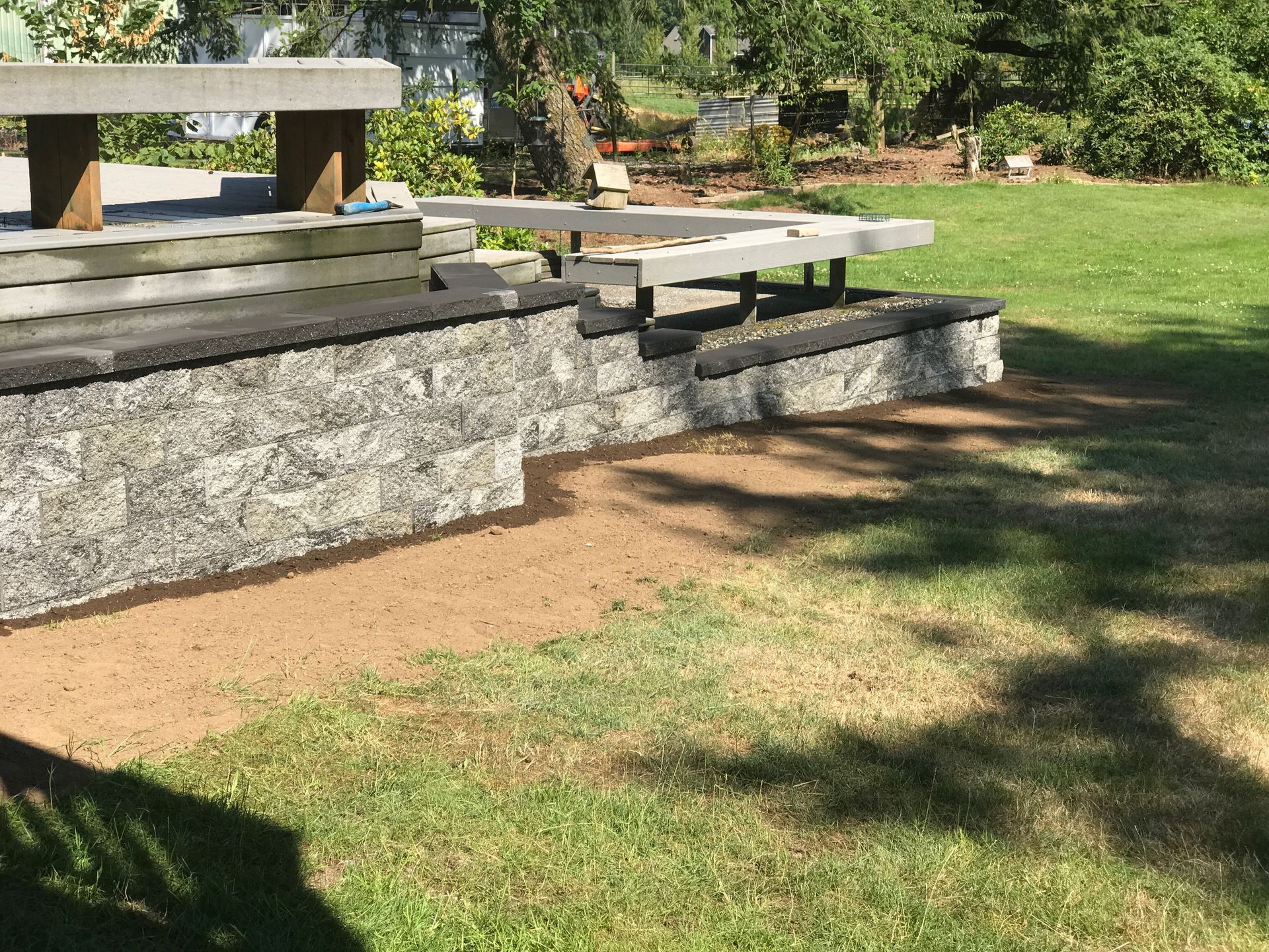 Stone picnic table and benches on a grassy park lawn under a tree