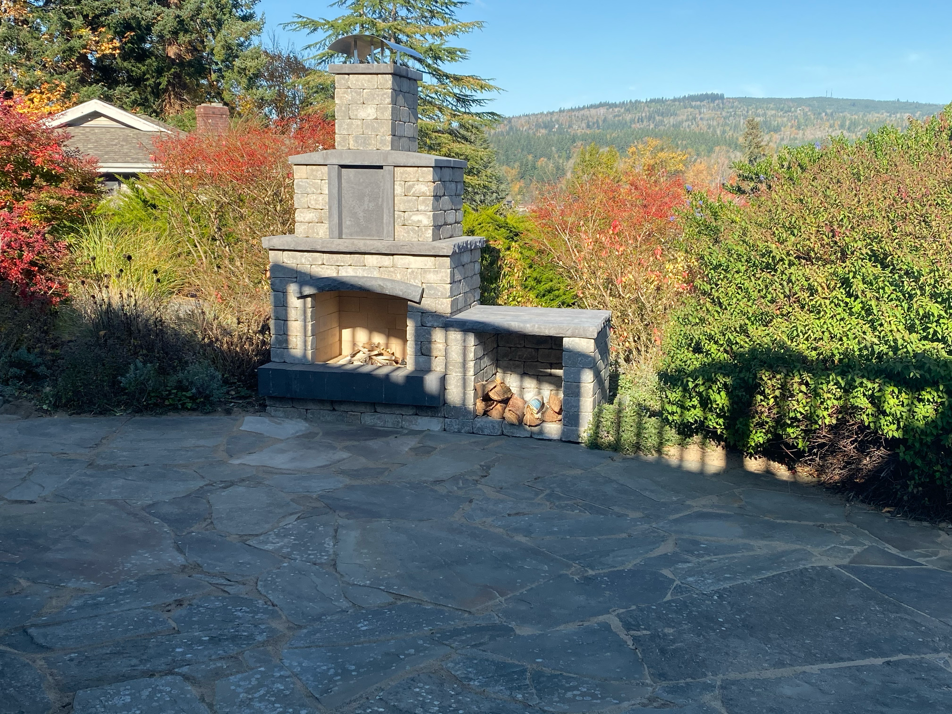 A beautiful stone patio with a fire pit in a Pacific Northwest backyard setting.