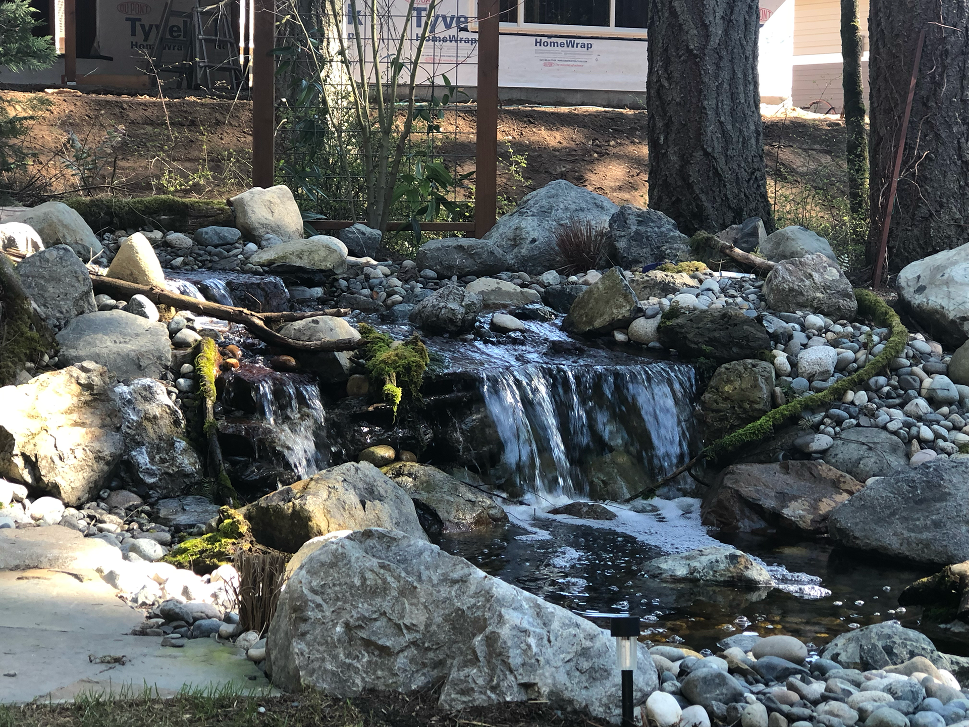 Small rocky waterfall in a landscaped garden with flowing water and trees