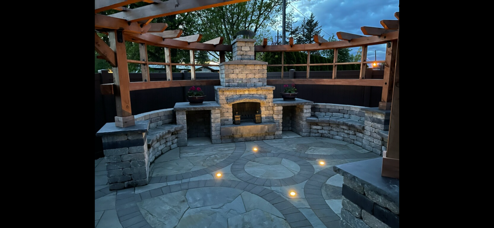 Stone fire pit with benches in a circular outdoor pavilion at dusk