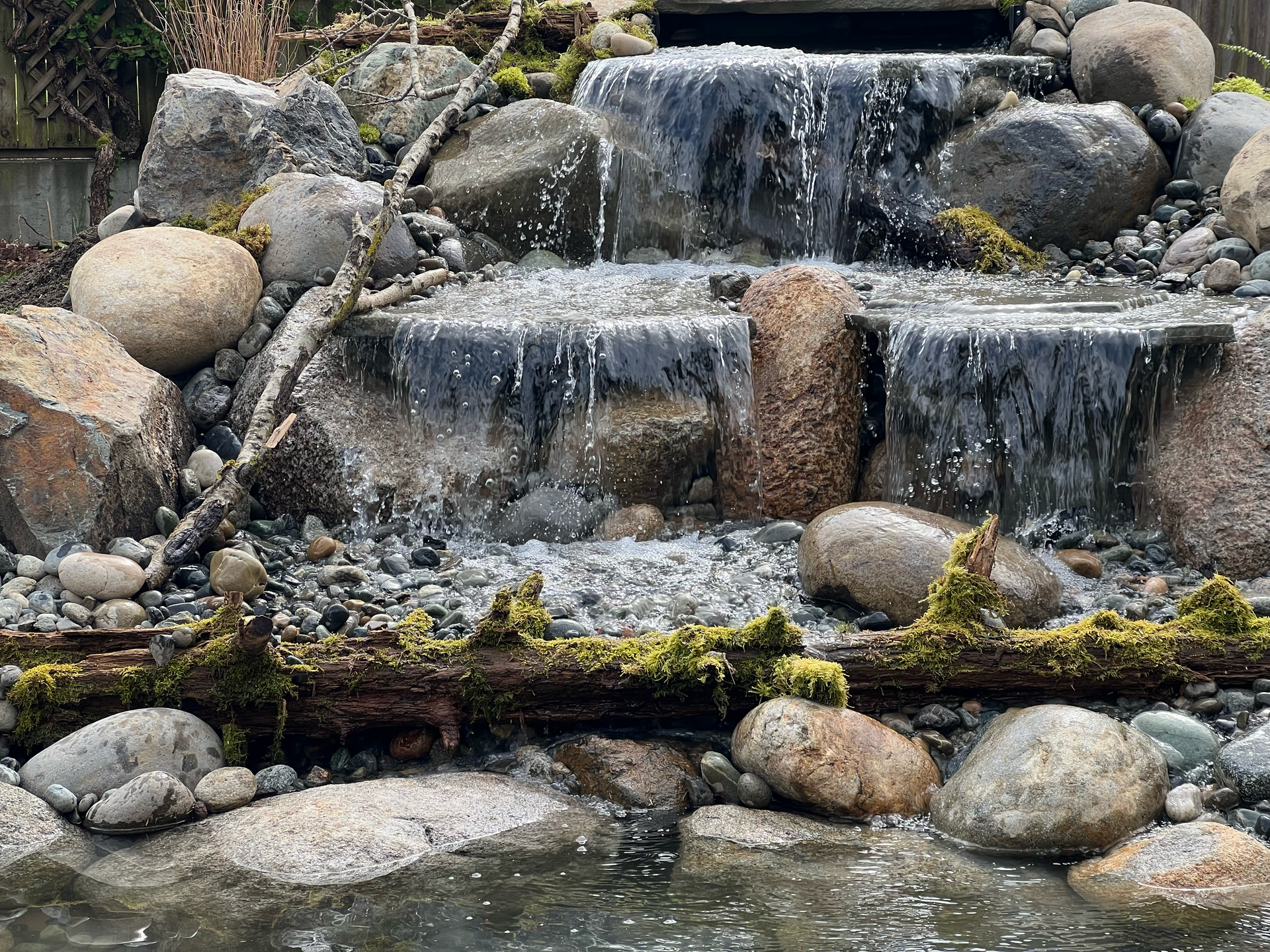 Rock garden waterfall cascading over stacked stones into a shallow stream