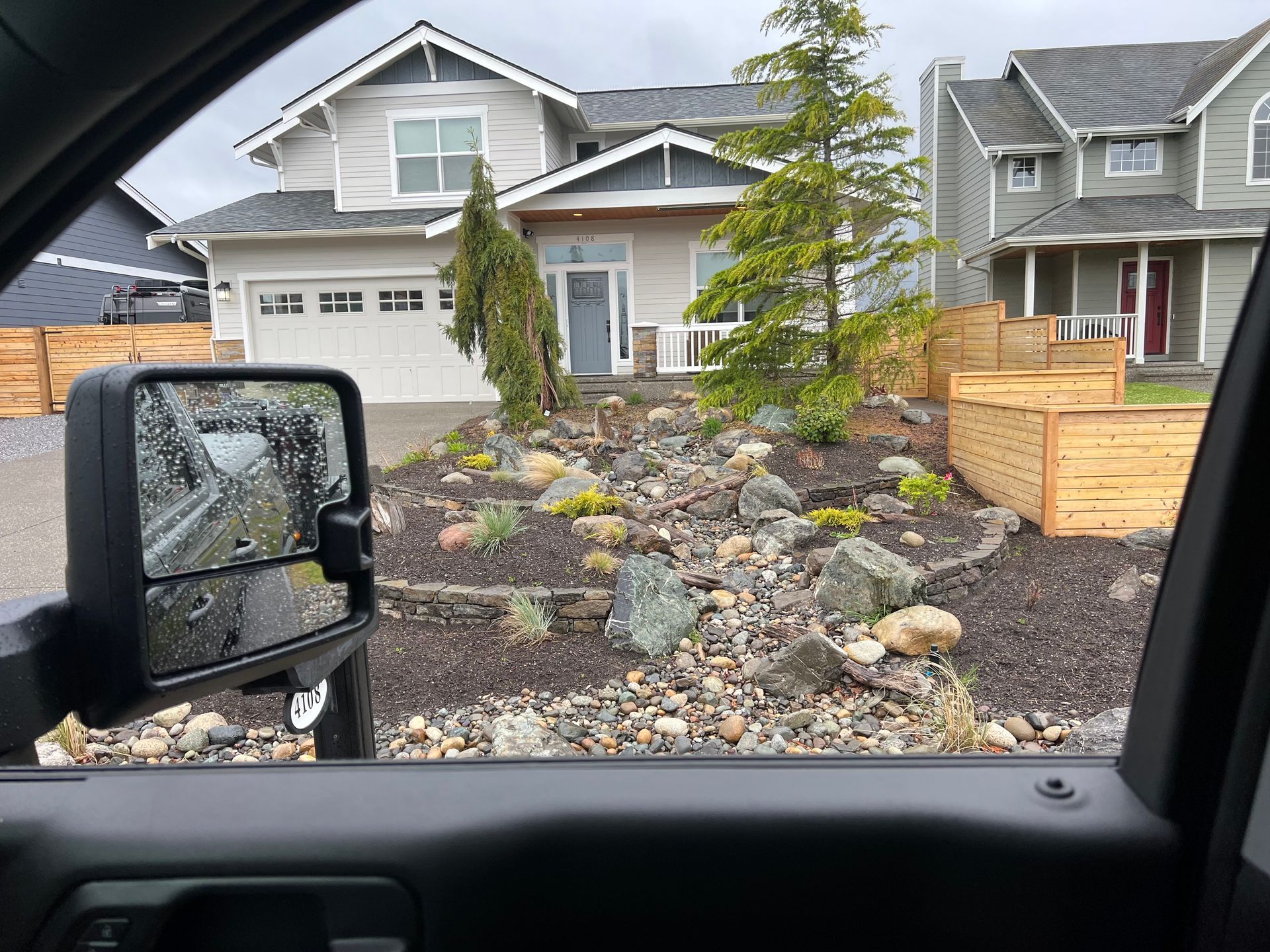 New house under construction with rock landscaping, viewed from inside a vehicle