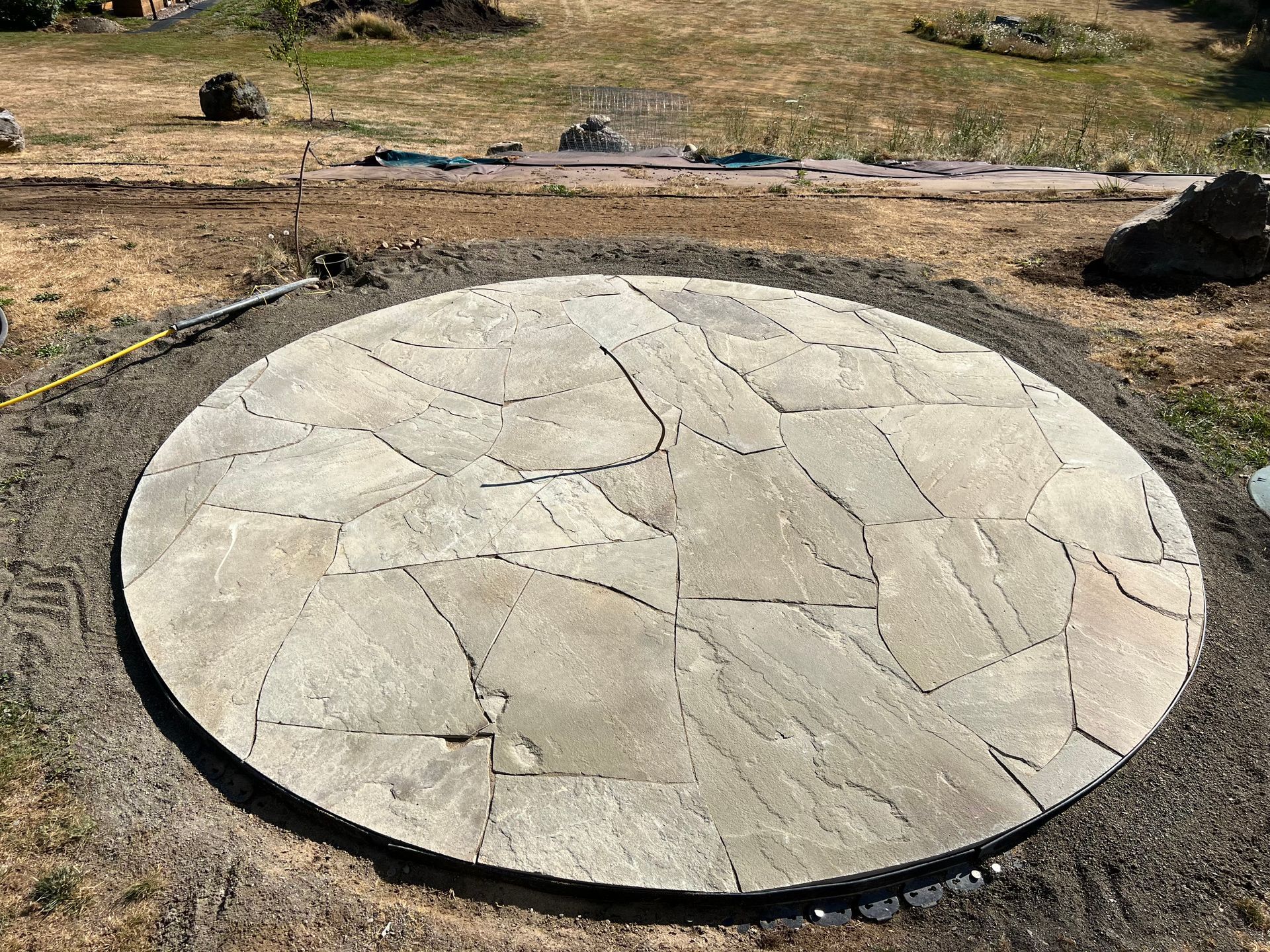 Round stone patio base on bare ground at a construction site