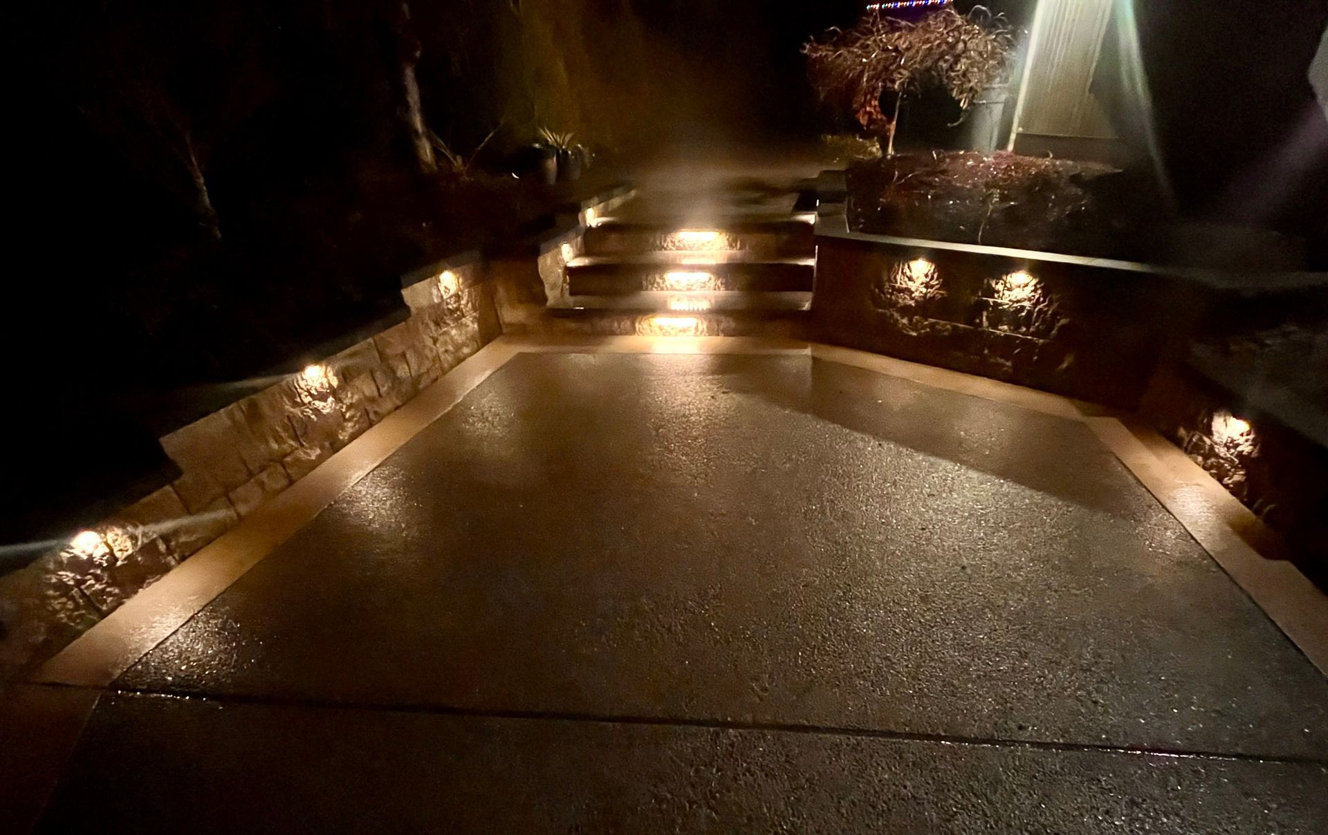 Illuminated stone steps and walkway at night, with glowing lights along the edges and dark surroundings