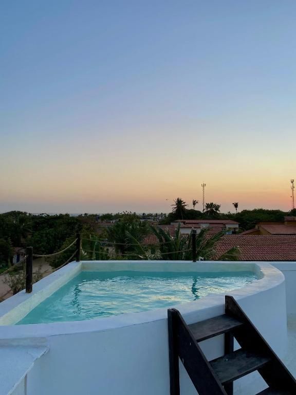 Pequena piscina na cobertura ao pôr do sol, com água azul e uma escada escura em primeiro plano.