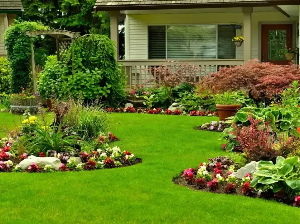 Lush front yard garden with colorful flower beds in front of a house and porch